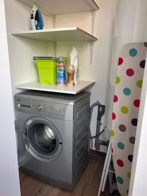 a laundry room with a washing machine and shelves at Appartement Résidence in Ajaccio