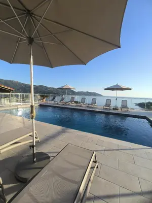 a patio with an umbrella and a swimming pool at Résidence Roc e Mare in Tiuccia