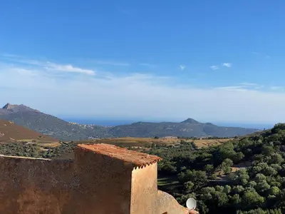 a building with a view of the ocean and mountains at Casa Padume - Maison de village en Balagne in Nessa