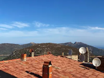 a roof with satellite dishes and mountains in the background at Casa Padume - Maison de village en Balagne in Nessa