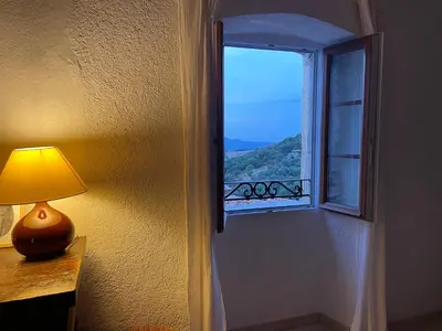 a lamp sitting on a table next to a window at Casa Padume - Maison de village en Balagne in Nessa