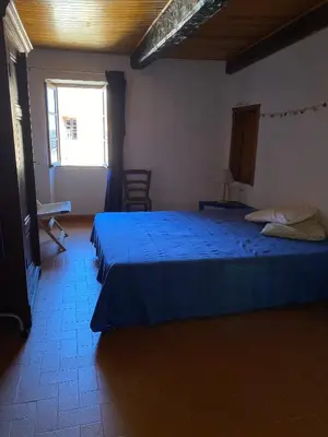 a bedroom with a blue bed and a window at Casa Padume - Maison de village en Balagne in Nessa