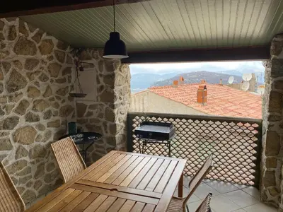 a wooden table and chairs on a balcony with a view at Casa Padume - Maison de village en Balagne in Nessa
