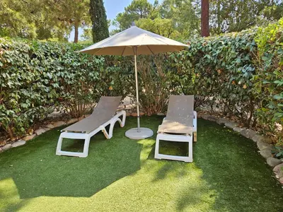 two chairs and an umbrella on the grass at ST CYPRIEN A6 5 pers à 250m de la plage de sable Saint Cyprien in Lecci
