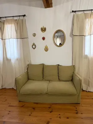 a couch in a living room with curtains and a mirror at Ferme auberge U sapè fà in Saliceto