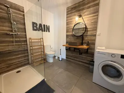a bathroom with a washing machine and a wooden wall at Bas de villa 80m2 secteur Ajaccio in Tavaco