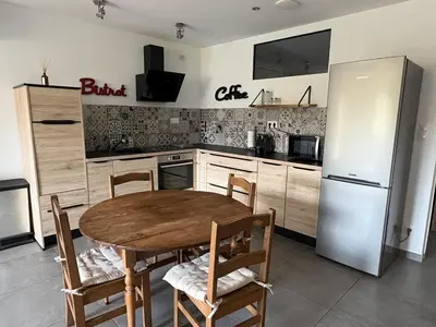 a kitchen with a wooden table and a refrigerator at Bas de villa 80m2 secteur Ajaccio in Tavaco