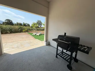 a grill in a room with a view of a patio at Bas de villa 80m2 secteur Ajaccio in Tavaco