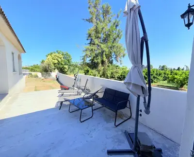 a patio with an umbrella and chairs and a table at Studio vue sur les clémentiniers in Santa-Lucia-di-Moriani