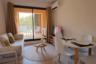 a living room with a couch and a table at Stéphi - Superbe T2 accès plage, piscine chauffée in Pianottoli-Caldarello