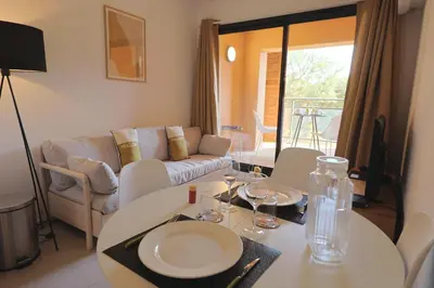 a living room with a table and a couch at Stéphi - Superbe T2 accès plage, piscine chauffée in Pianottoli-Caldarello