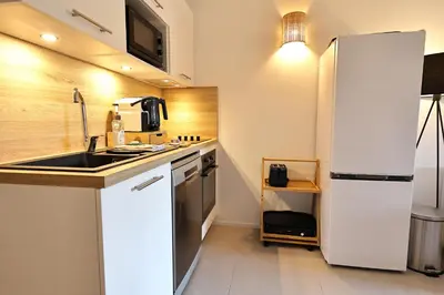 a kitchen with a white refrigerator and a sink at Stéphi - Superbe T2 accès plage, piscine chauffée in Pianottoli-Caldarello