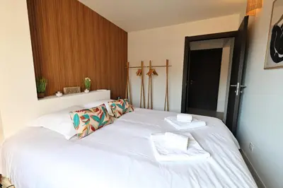 a bedroom with a large white bed with two pillows at Stéphi - Superbe T2 accès plage, piscine chauffée in Pianottoli-Caldarello