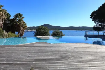 a large swimming pool next to a body of water at Stéphi - Superbe T2 accès plage, piscine chauffée in Pianottoli-Caldarello