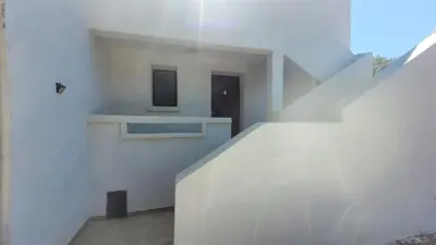 a white building with stairs with a window and a door at Location de vacances in Santa-Maria-Poggio