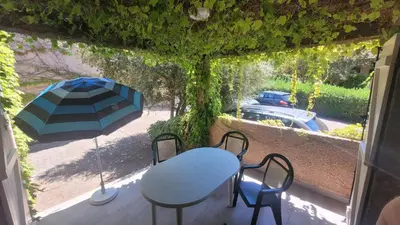 a patio with a table and chairs and an umbrella at Location de vacances in Santa-Maria-Poggio