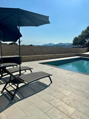 a chair with an umbrella next to a swimming pool at Appartement avec terrasse privée et piscine in Sarrola-Carcopino