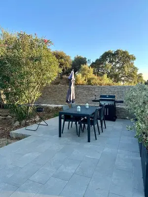 a patio with a table and chairs and a grill at Appartement avec terrasse privée et piscine in Sarrola-Carcopino