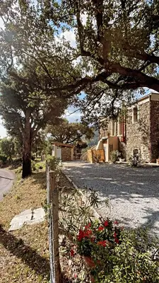 a fence in front of a house with red flowers at Demeure de charme, appartement du Campu di l altru mondu in San-Giuliano
