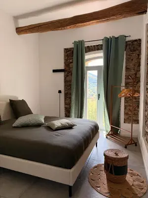 a bedroom with a bed and a large window at Demeure de charme, appartement du Campu di l altru mondu in San-Giuliano