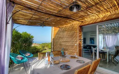 a dining room with a table and chairs on a patio at Rez de villa vue mer panoramique in Albitreccia