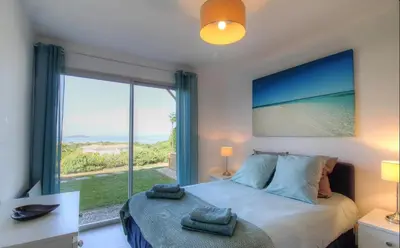 a bedroom with a bed with a view of the ocean at Rez de villa vue mer panoramique in Albitreccia