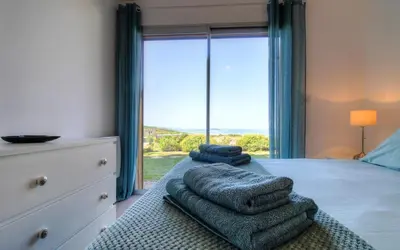 a bedroom with a bed with towels on it with a window at Rez de villa vue mer panoramique in Albitreccia