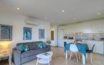 a living room and kitchen with a couch and a table at Rez de villa vue mer panoramique in Albitreccia