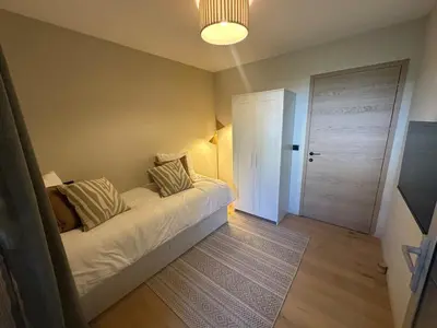 a bedroom with a white bed with pillows and a door at Appartement exceptionnel vue mer in Ajaccio