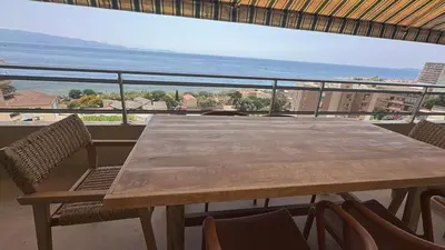 a table and chairs on a balcony with a view of the ocean at Appartement exceptionnel vue mer in Ajaccio