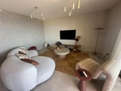 a living room with two white chairs and a tv at Appartement exceptionnel vue mer in Ajaccio