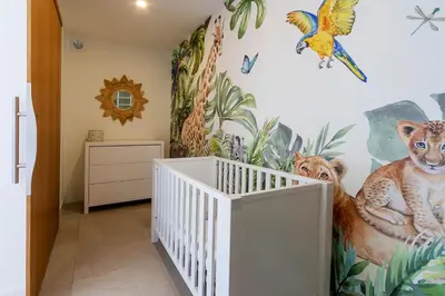 a nursery with a white crib and jungle themed wall at Villa Lalie in Olmeto