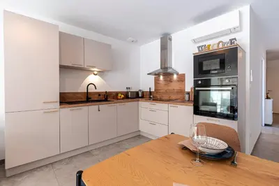 a kitchen with white cabinets and a wooden table at L'Île de Beauté - Climatisé in Pietrosella