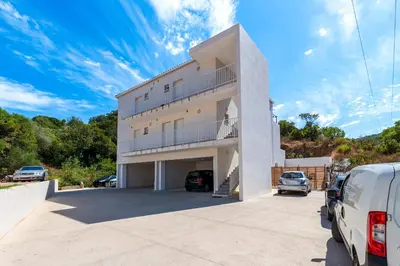 a large white building with cars parked in a parking lot at L'Île de Beauté - Climatisé in Pietrosella