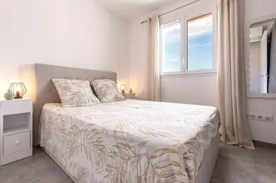a white bedroom with a bed and a window at L'Île de Beauté - Climatisé in Pietrosella