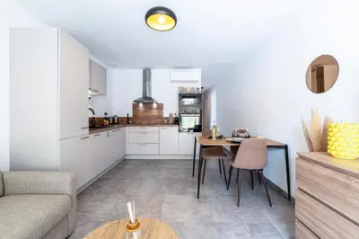 a living room with a table and a kitchen at L'Île de Beauté - Climatisé in Pietrosella