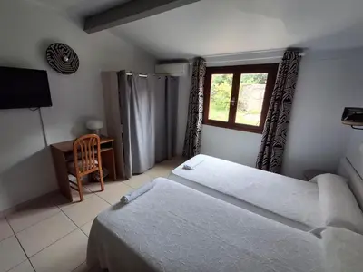 a bedroom with two beds and a window and a chair at Grand T2 duplex, terrasse et jardin in Porto Ota