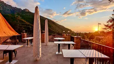 a patio with tables and umbrellas and the sunset at Grand T2 duplex, terrasse et jardin in Porto Ota