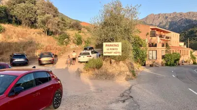 a red car parked on the side of a road with a sign at Grand T2 duplex, terrasse et jardin in Porto Ota