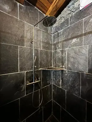a shower in a bathroom with a stone wall at Bergerie in Volpajola