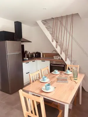 a kitchen with a wooden table with chairs and a refrigerator at Villa Poggiole in San-Nicolao