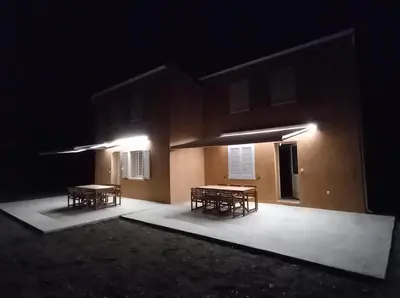 two tables on the side of a building at night at Villa Poggiole in San-Nicolao