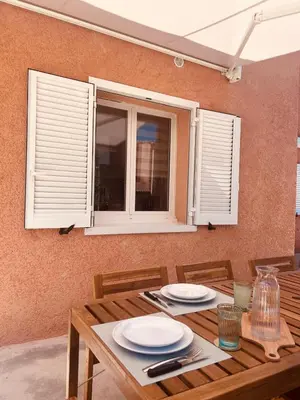 a wooden table with chairs and a window at Villa Poggiole in San-Nicolao