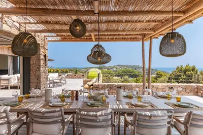 a table and chairs on a patio with a view at Villa Bonanza Di Cala Rossa in Lecci