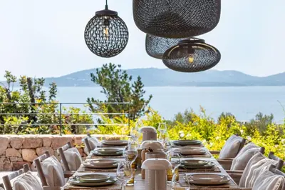 a long dining table with white chairs and lights at Villa Bonanza Di Cala Rossa in Lecci