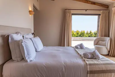 a bedroom with a white bed with a chair and a window at Villa Bonanza Di Cala Rossa in Lecci