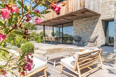 a patio with two wooden benches and flowers at Villa Fautea Di Santa Lucia in Sainte-Lucie de Porto-Vecchio