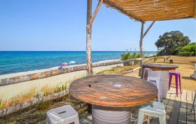 a table and chairs on the beach next to the ocean at 2 Bedroom Cozy Apartment In Prunete in Prunete