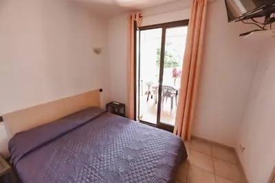 a bedroom with a bed and a sliding glass door at Casa l'Ascosu 2 in Coggia