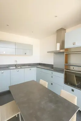 a kitchen with white cabinets and a table with chairs at Evasion Méditerranée - Vue Mer in Ajaccio